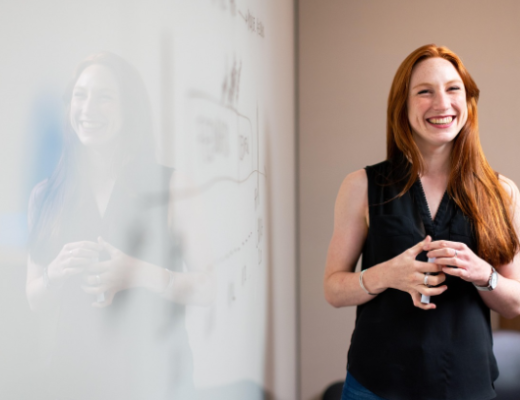 Smiling Woman Wearing Black Dress Standing in Front of a Room